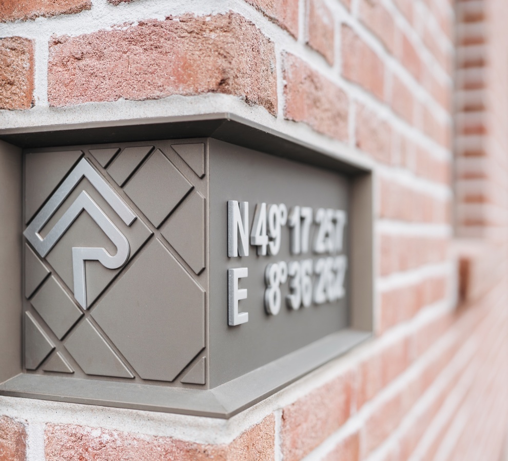 In die Klinkerfassade eingelassene Metalltafel mit Logo und den Koordinaten der Reitanlage